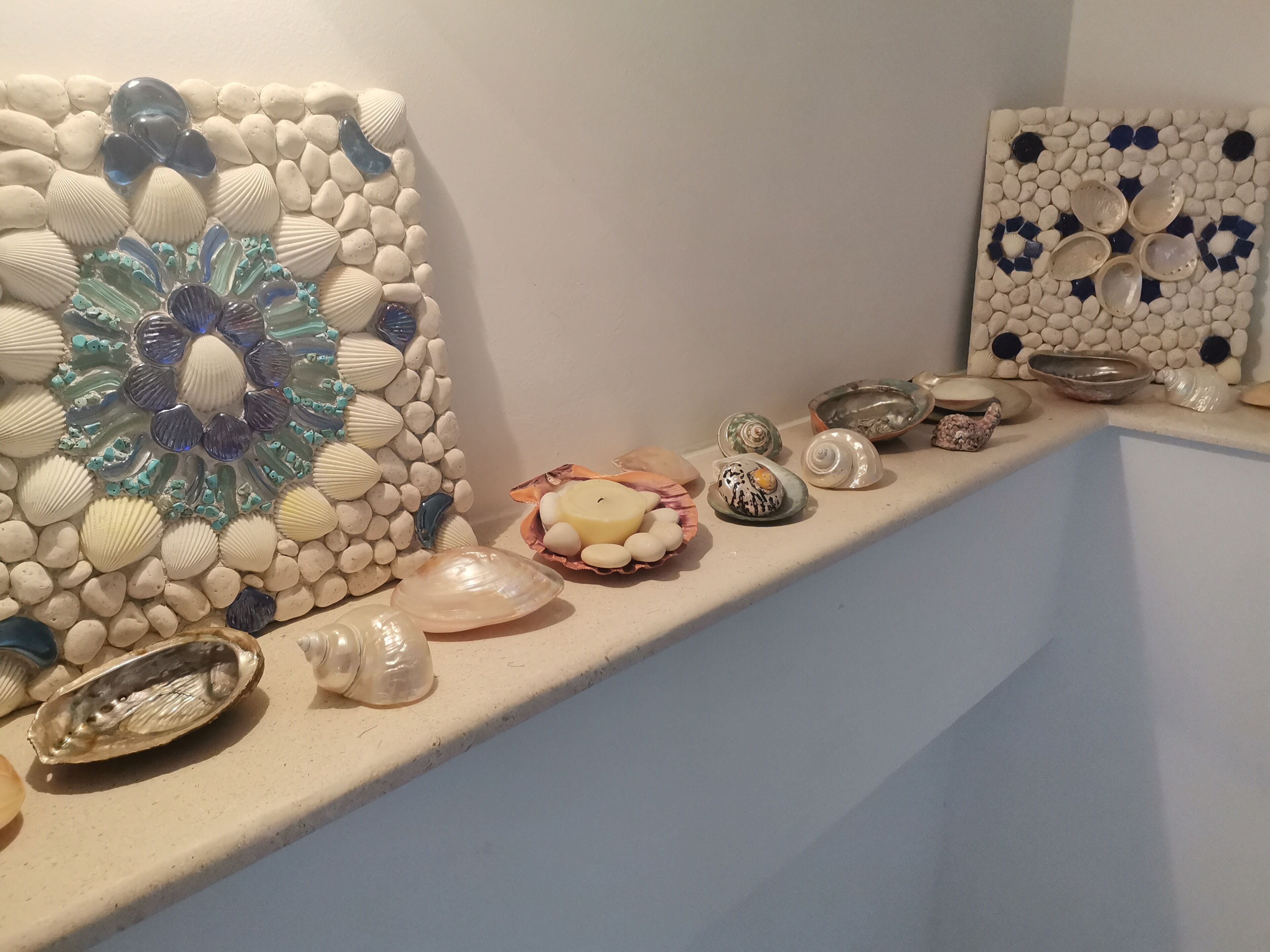 Une étagère ornée d’objets décoratifs, notamment des coquillages, des œuvres d’art en verre et des pièces en céramique.