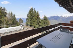A balcony with a table and chairs overlooking a snowy mountain range and a forested area. - Magnificent apartment in Thyon-les-Collons (Vex)