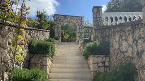 A stone staircase leading up to a stone archway, surrounded by greenery and stone walls. - Private Villa and Pool With Lake Views and Sunset Terraces at The Grove (Corfu)
