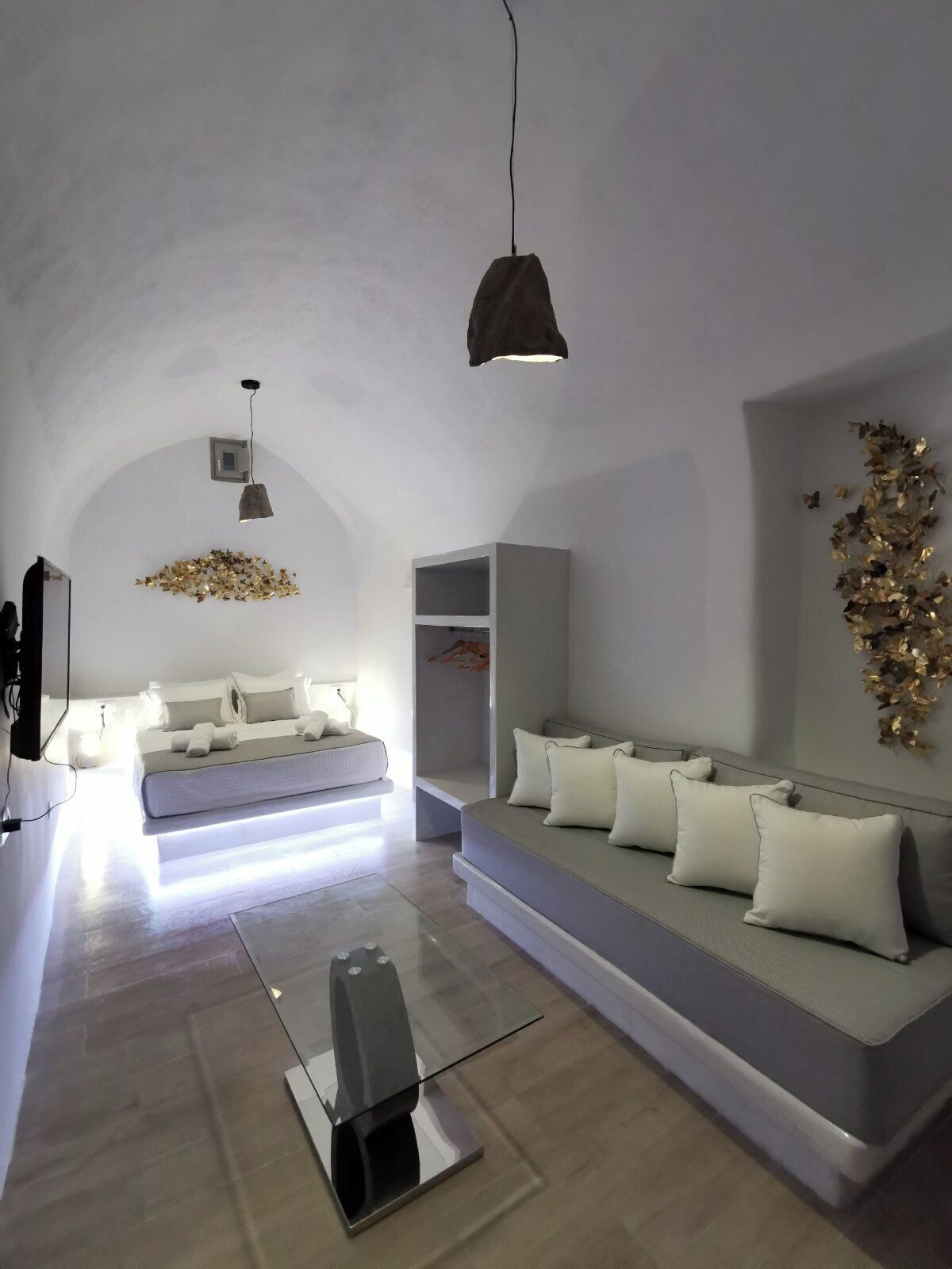 A modern bedroom with a bed, a sofa, a TV, and a decorative wall piece.