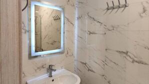 Ein Badezimmer mit Marmorwand, Waschbecken, Spiegel und Dusche.