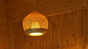 Una habitación de madera con una cama, dos lámparas de noche y un aplique.