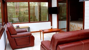 Una habitación acogedora con un sofá de cuero marrón, una mesita de madera y un televisor.