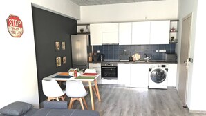 A modern kitchen with a dining area, a sofa, and a washing machine. - Pegasus Amazing Flat, 1,5min Walk To The (Chania)