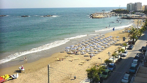 A beach with umbrellas, a pier, and buildings in the background. - Pegasus Amazing Flat, 1,5min Walk To The (Chania)