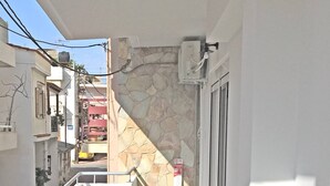 A balcony with a table and chairs, a stone wall, and a view of the street. - Pegasus Amazing Flat, 1,5min Walk To The (Chania)