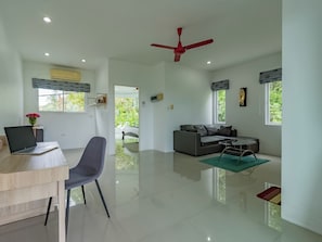 A spacious living area with a modern design, a dining area, and a workspace with a laptop. - Villa Nap Dau Crown Private Pool Villa Phuket (Chalong)