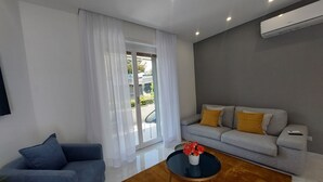 A modern living room with a grey sofa, blue armchair, and a round coffee table with a vase of flowers. - Vanesia's Luxury Suits (Sanremo)