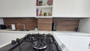 A modern kitchen with a gas stove, white cabinets, and a marble countertop. - Vanesia's Luxury Suits (Sanremo)