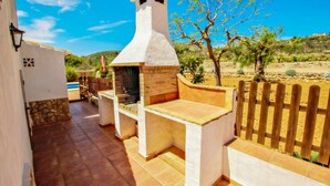 A patio with a stone floor, a white wall, and a wooden fence. - Quicano - magnificent views and private pool in Lliber (Lliber)
