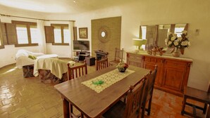 A dining area with a wooden table, chairs, a television, and a kitchen area with cabinets and a mirror. - Quicano - magnificent views and private pool in Lliber (Lliber)