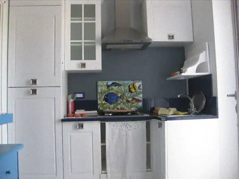 A compact kitchen with white cabinets, a microwave, and a painting of tropical fish.