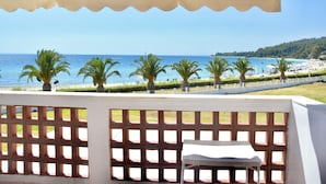 Uma varanda com vista para o mar, palmeiras e um cercado branco.