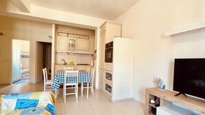 Un espacio habitable compacto con comedor, kitchenette y televisor.