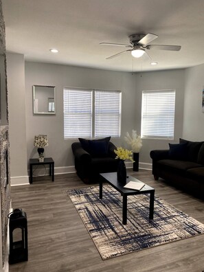 Relax in style with a comfortable sofa and armchair, surrounded by natural light and a beautiful floral touch.