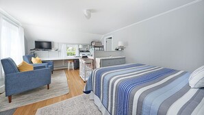 Moderni, hyvin valaistu makuuhuone, jossa on suuri sänky, työpöytä ja televisio.