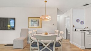Un espace repas comprenant une table ronde, des chaises et un luminaire suspendu.