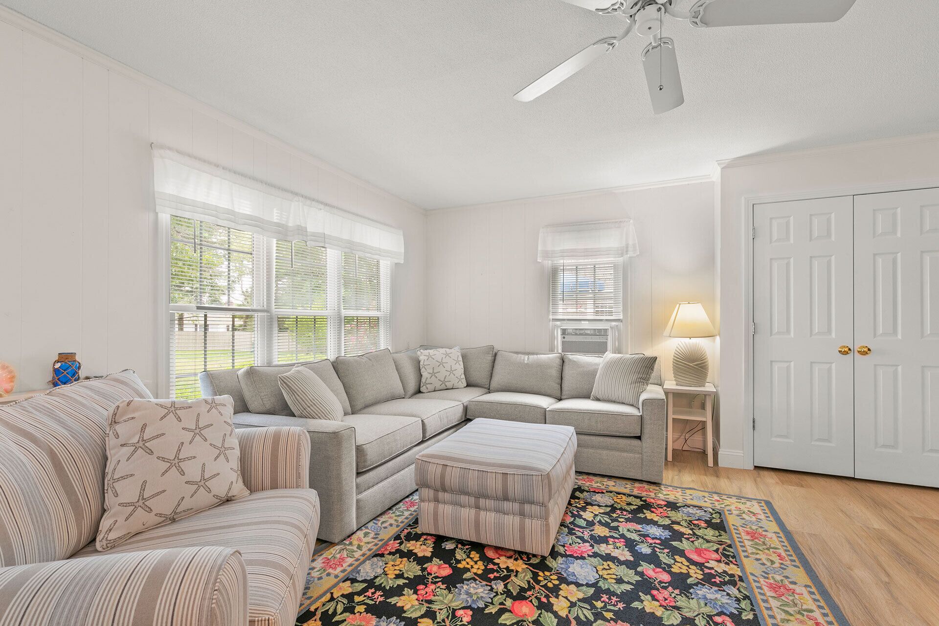A living room with a sectional sofa, ottoman, and a floral rug.