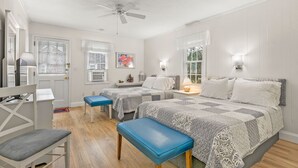 Une chambre avec deux lits, un bureau, une chaise et un ventilateur de plafond.