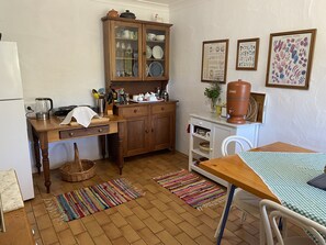 Een compacte keuken met houten kastjes, een eettafel en een koffieapparaat.