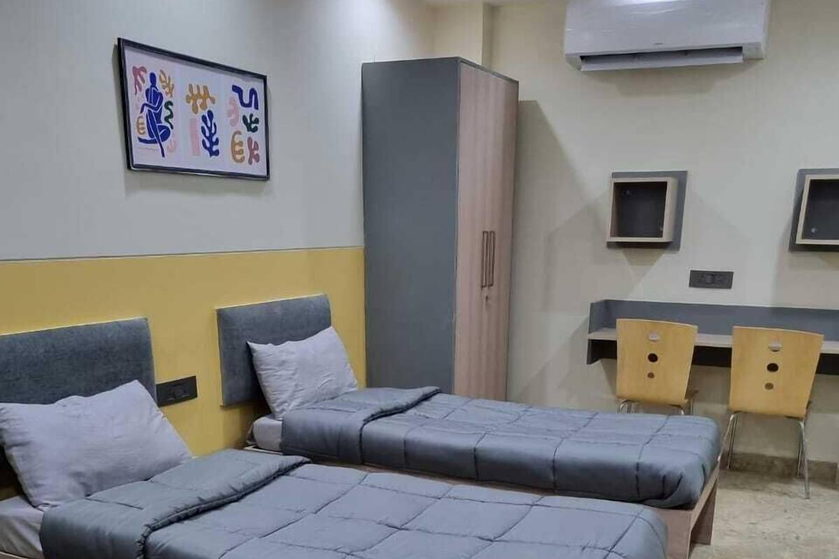 Een kamer met twee bedden, een bureau en een kledingkast.
