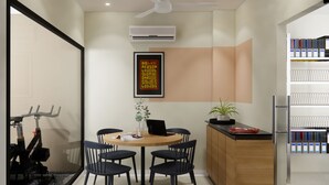A modern kitchen with a round table, chairs, a ceiling fan, and a bookshelf.