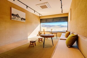 A cozy room with a sofa, a small round table, and a window with a view of a desert landscape.