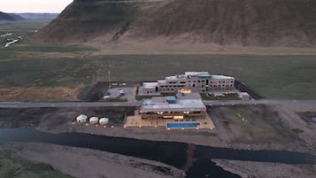 A modern building with multiple floors, a parking area, and a small water body in front.