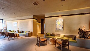 A modern lobby with a central seating area, a large abstract painting, and a wooden sculpture. - Steppe Valley Resort (Xing'an)