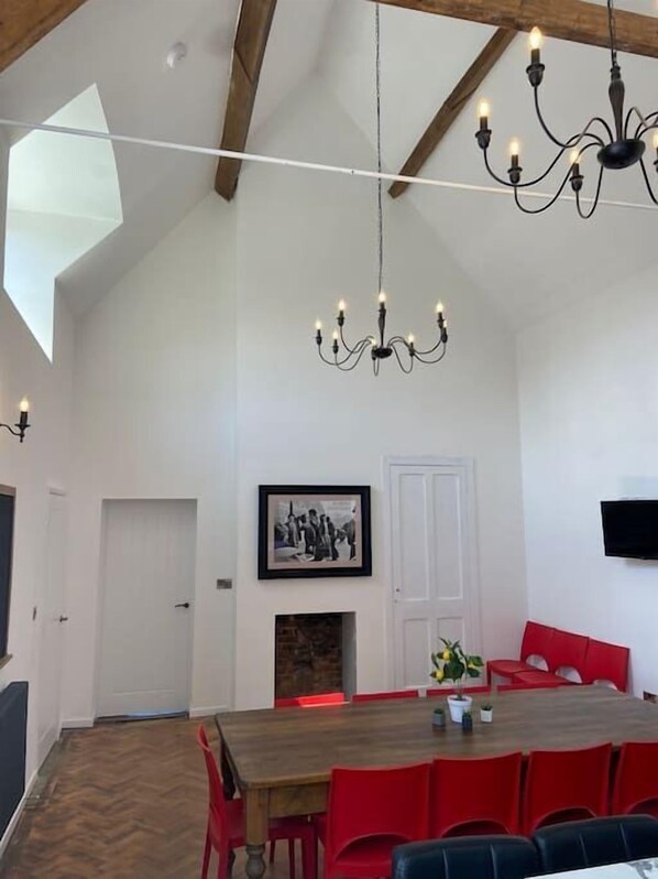 A dining area with a wooden table, red chairs, a chandelier, and a framed picture on the wall.