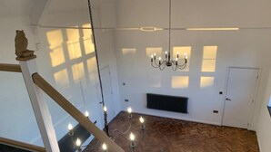 A spacious room with a herringbone floor, a chandelier, a radiator, and a door. - Bodham House & Halls - 9 bedrooms (Bodham)