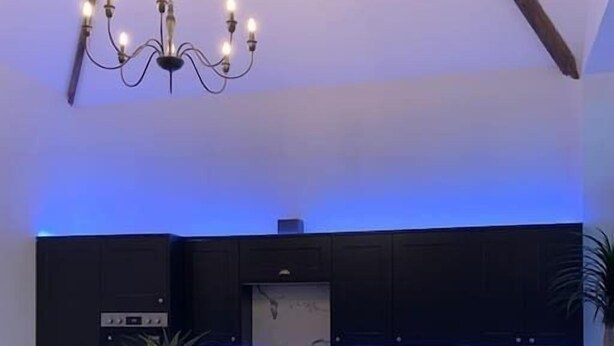Una cocina moderna con armarios oscuros, una isla central y una araña.