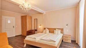 Een slaapkamer met een houten bed, een stoel, een nachtkastje, een spiegel en een kroonluchter.