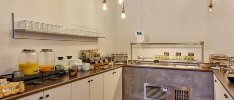 A breakfast bar with a glass display case, a coffee station, and a juice bar.