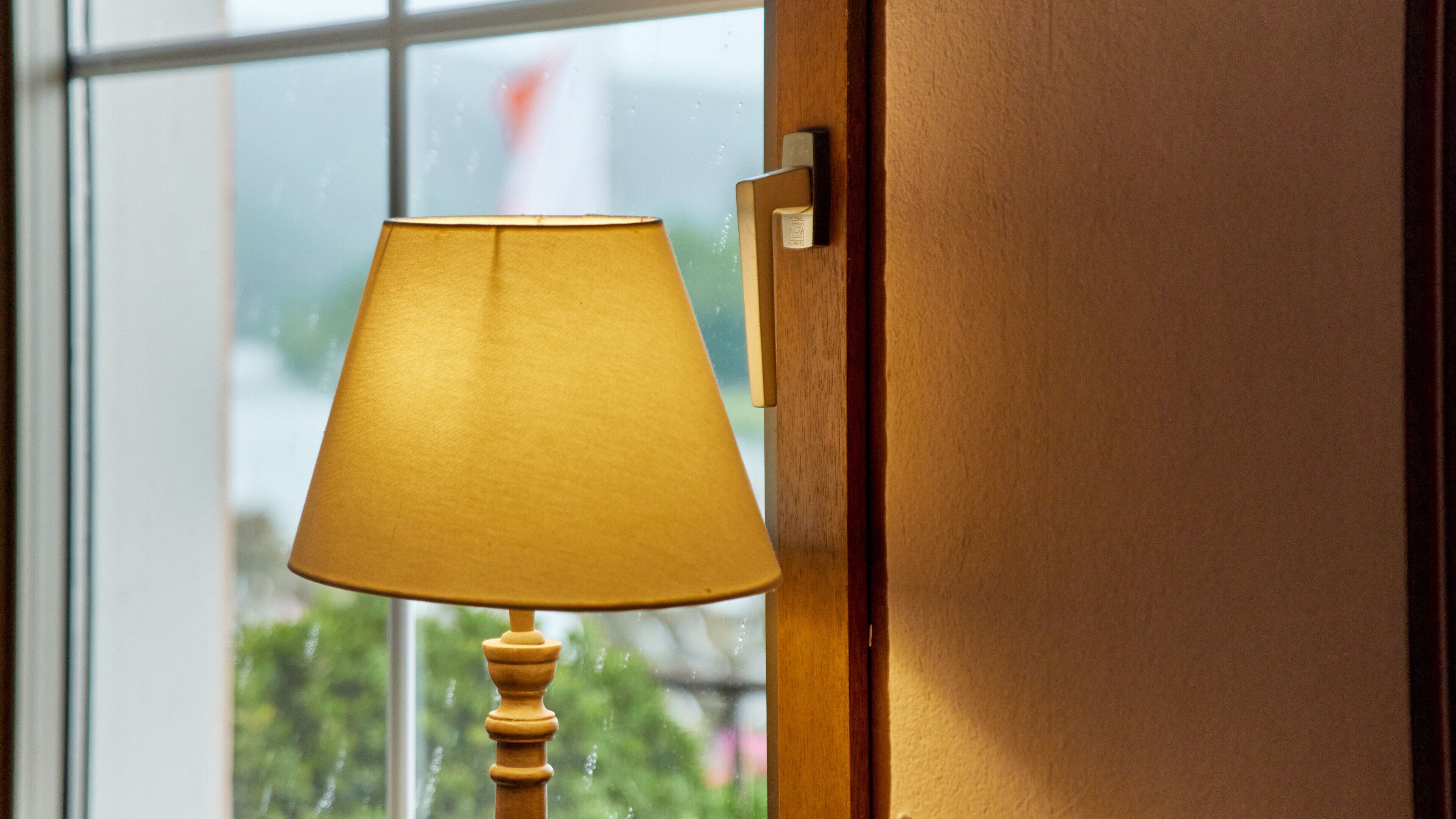 Une lampe avec un abat-jour jaune, placée à côté d’une porte en bois.