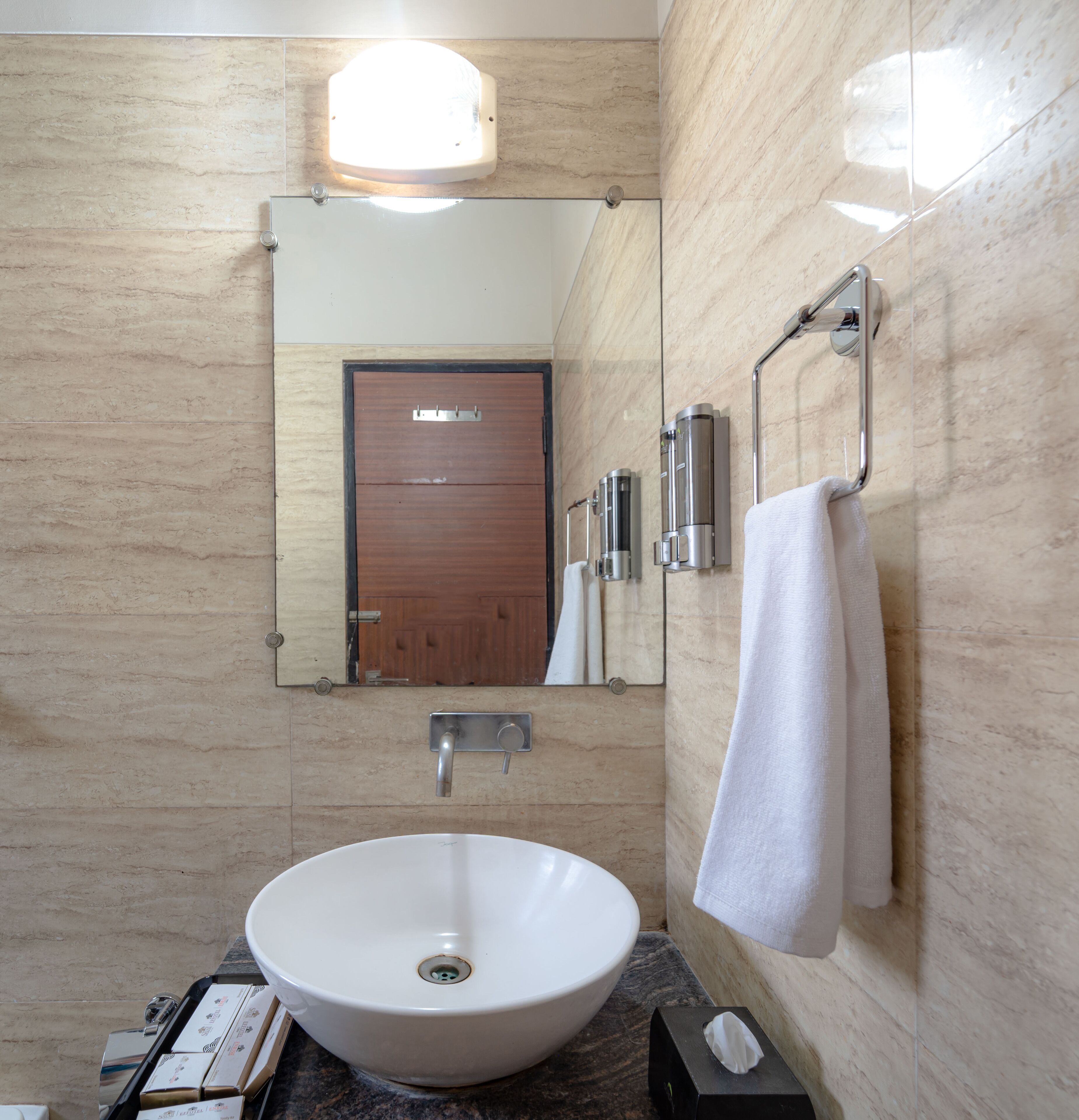 A bathroom with a white sink, a mirror, a towel, and a door.