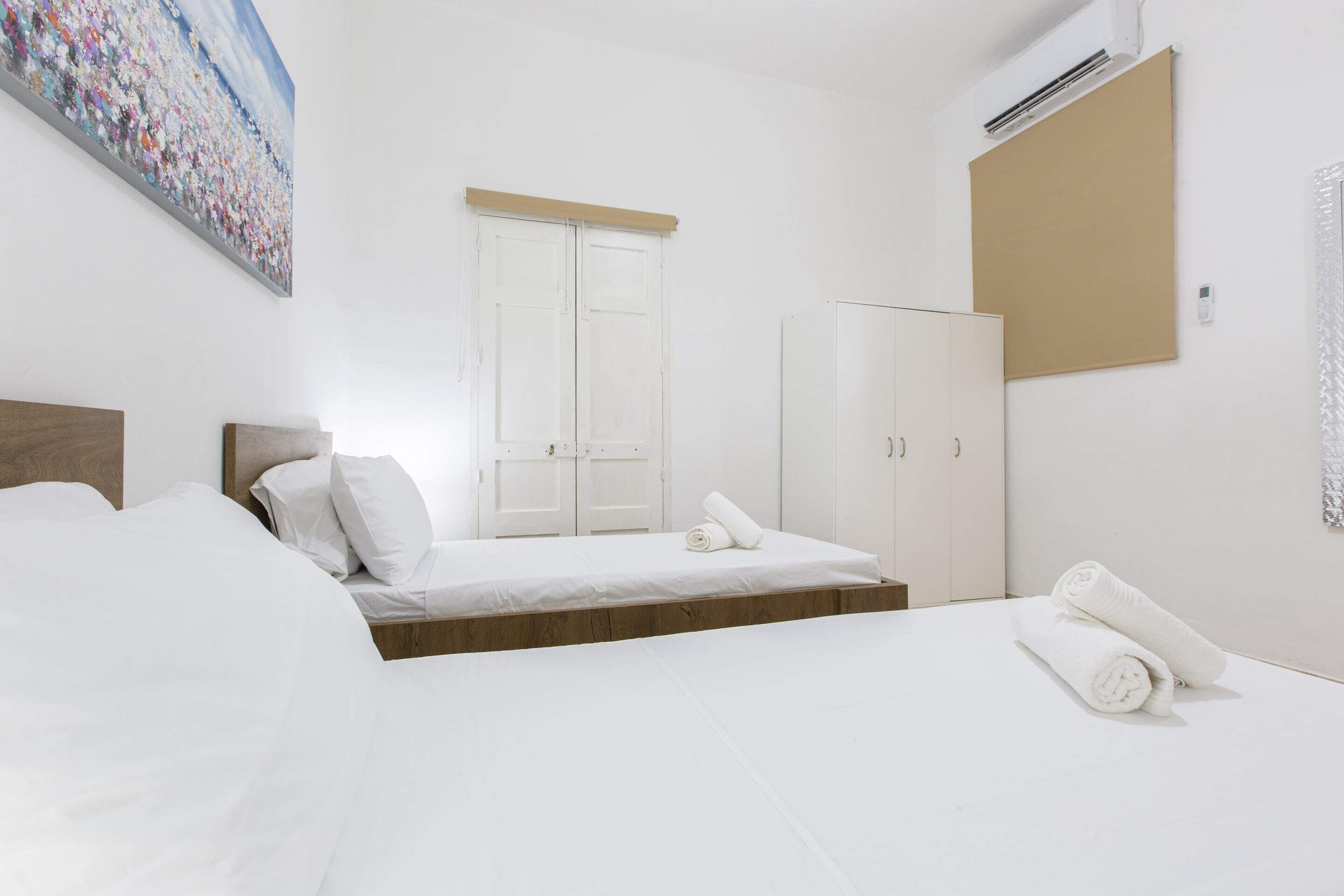 Habitación de hotel minimalista con cama, armario y un cuadro en la pared.