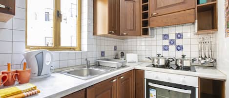 Una cocina con armarios de madera, encimera blanca, horno empotrado y una ventana.