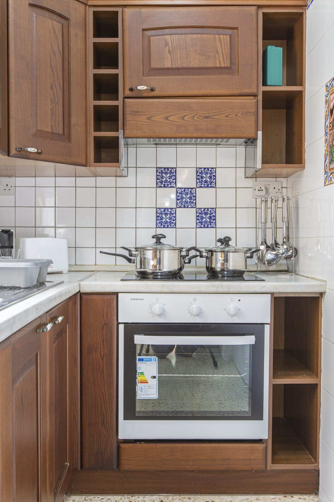 Une cuisine avec des meubles en bois, un fourneau blanc et un pare-feu en carreaux.