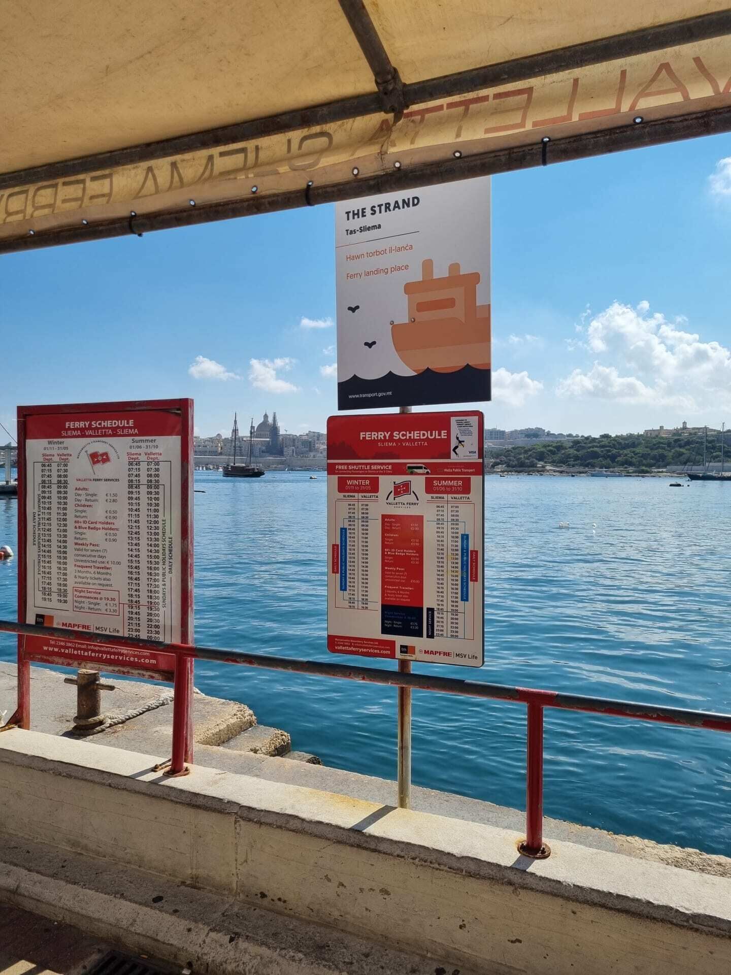 A ferry schedule board with a cityscape in the background.