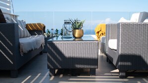 A rooftop terrace with wicker furniture, a glass coffee table, and potted plants. - Pool Penthouse (Swieqi)