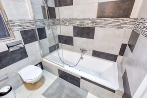 A modern bathroom with a bathtub, toilet, and a glass-enclosed shower area. - Pool Penthouse (Swieqi)