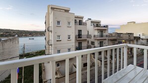 A multi-story residential building with balconies, a view of the sea, and a clear sky. - Golden Flat in San Pawl (St. Paul's Bay)