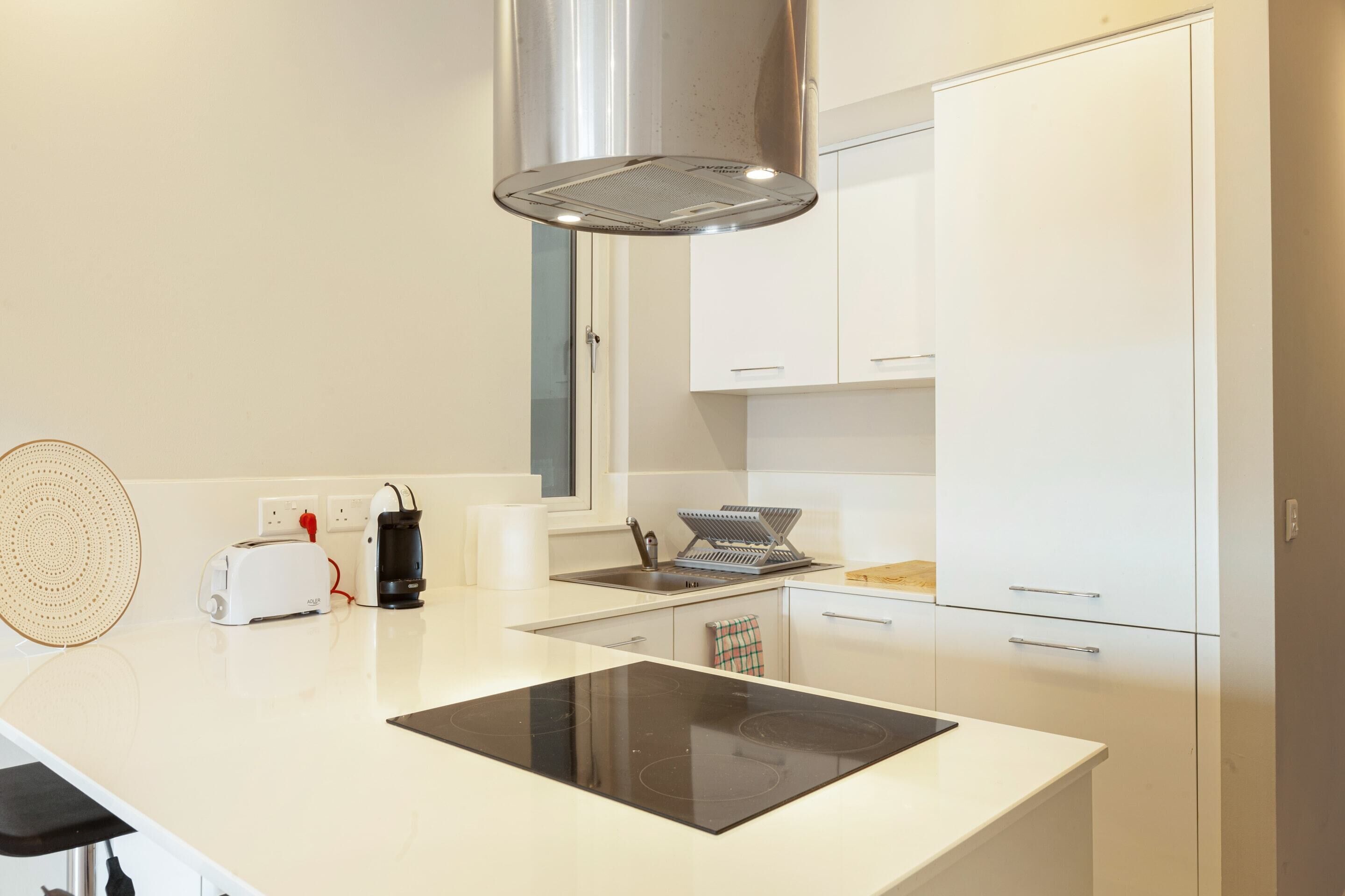 A modern kitchen with a central island, built-in oven, and white cabinetry.
