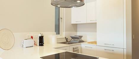 A modern kitchen with a central island, built-in oven, and white cabinetry.