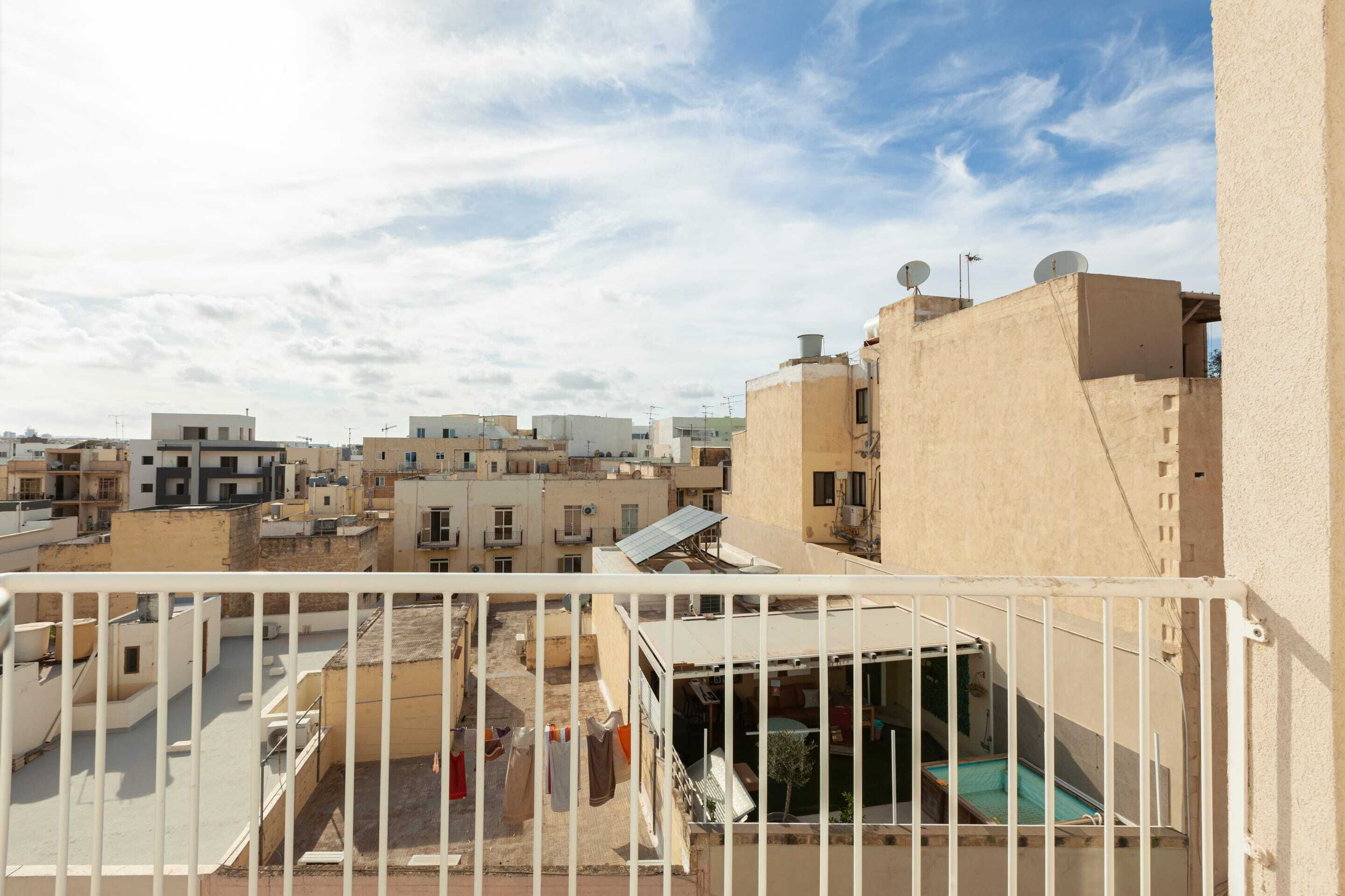Zona residencial con varios edificios, algunos con antenas parabólicas, y un balcón con ropa tendida.