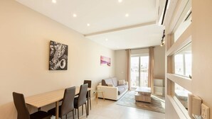 A modern living room with a dining area, a sofa, and a coffee table. - Brand new 1BR in Central Malta (Pieta)