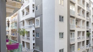 Un edificio residencial de varios pisos con balcones, una calle visible abajo y un cielo despejado.