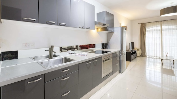 Una cocina moderna con armarios grises, electrodomésticos de acero inoxidable y encimera blanca.