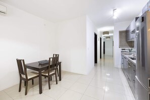 A modern kitchen with stainless steel appliances, a dining table with chairs, and a clean, white interior. - Sliema 2 Bedroom Apartment (Sliema)